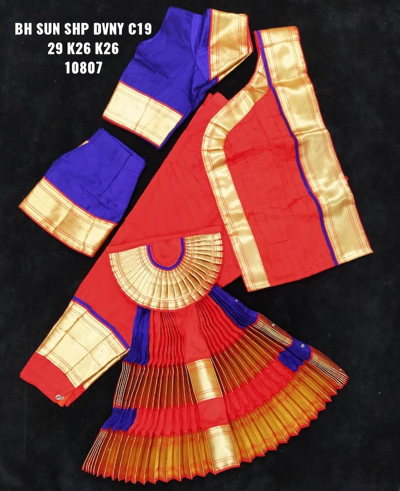 Puede incluir: Traje de danza indio rojo y azul con ribetes dorados. El traje incluye una falda, una blusa y una pieza decorativa para la cintura. El texto en la imagen dice "BH SUN SHP DVNY C19 29 K26 K26 10807".