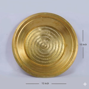 May include: A circular brass tray with a polished gold-toned finish, featuring concentric rings of embossed decorative patterns radiating from the center. The tray measures 15 inches in diameter, as indicated by the text labels on the image.