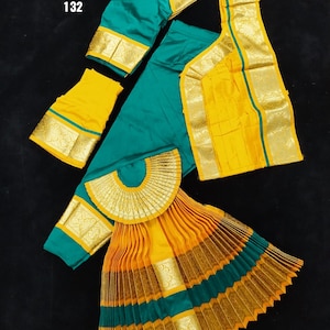 Puede incluir: Un traje de danza indio amarillo y turquesa con ribetes dorados. El traje incluye una falda, una blusa y una chalina. La falda est&aacute; plisada y tiene un dise&ntilde;o en forma de abanico en la parte superior. La blusa tiene un escote redondo y mangas cortas. La chalina es rectangular y tiene un borde decorativo. El texto "BH SUN SHP DVNY 25 K10 K13 132" est&aacute; impreso en la imagen.
