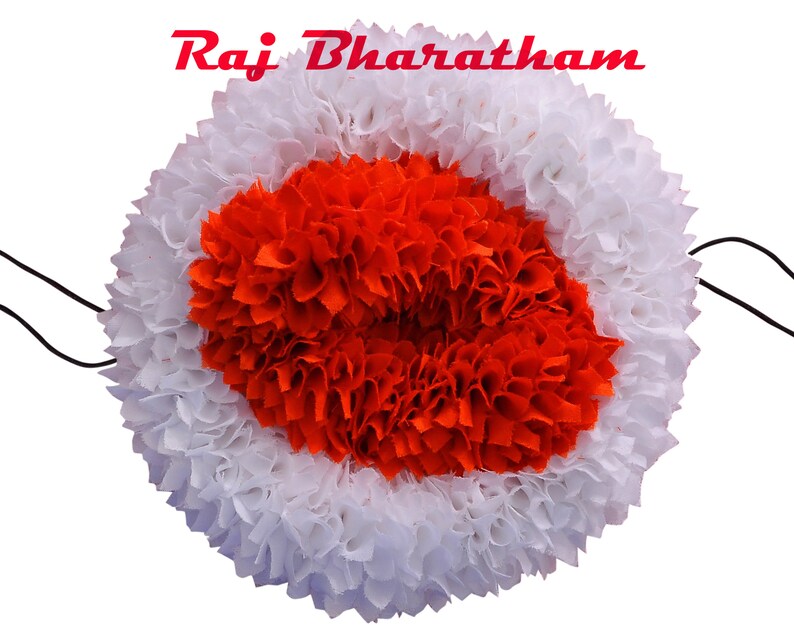 May include: A white and orange fabric flower garland with a black string attached. The garland is made of many small fabric flowers.