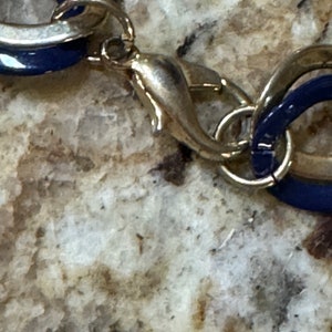 May include: A silver and blue chain necklace with a lobster clasp closure.