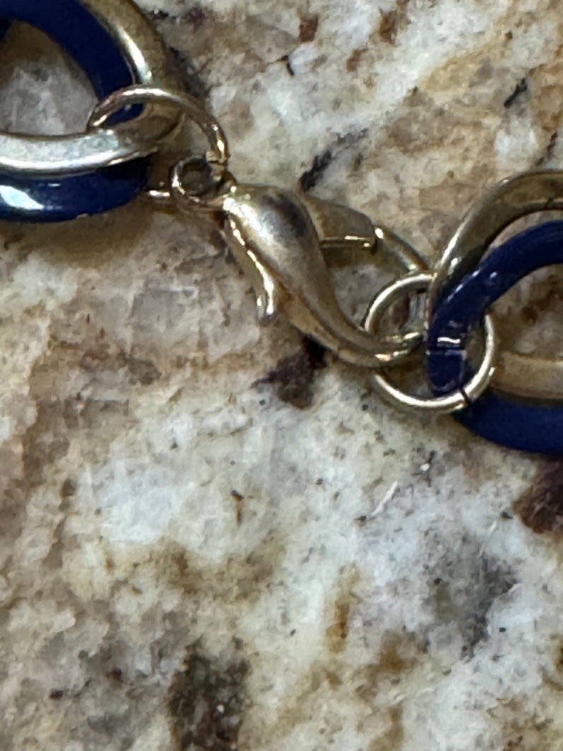 May include: A silver and blue chain necklace with a lobster clasp closure.