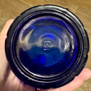 May include: Cobalt blue glass bottle with a textured rim and a square mark on the bottom.
