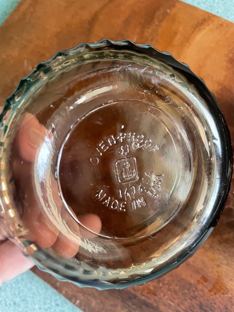 May include: A clear glass baking dish with a scalloped rim. The bottom of the dish has the text "Ovenproof" and "Made in USA" with an anchor logo.