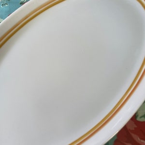 以下が含まれることがあります： 茶色と金色の縁取りのある白い楕円形のサービングプレート