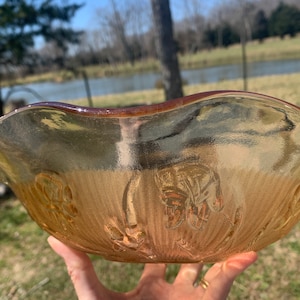 May include: A vintage, amber-coloured glass bowl with a scalloped rim and a floral design. The bowl has a textured surface and is perfect for serving snacks or desserts.