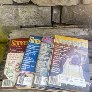 May include: Four vintage copies of "The Workbasket" magazine, a home arts and crafts magazine. The covers feature a variety of crafts, including crocheting, knitting, quilting, and canning. The magazines are stacked on top of each other, with the most recent issue on top.