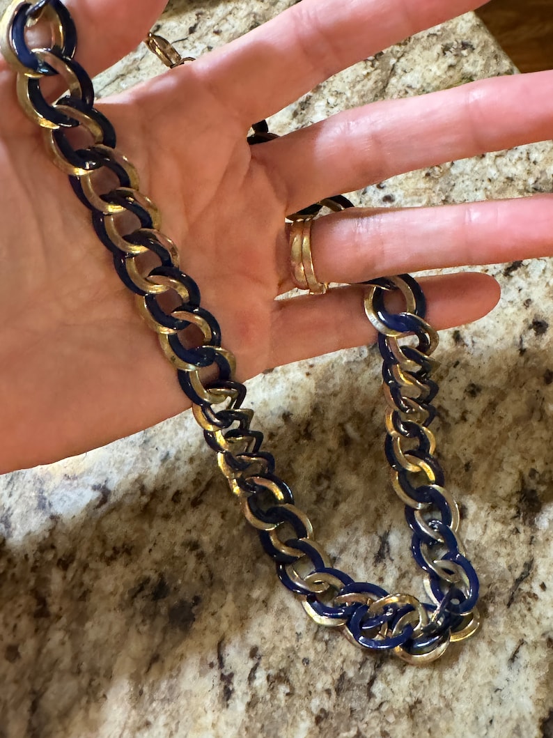 May include: A gold chain necklace with blue enamel accents. The chain is made of interlocking links.