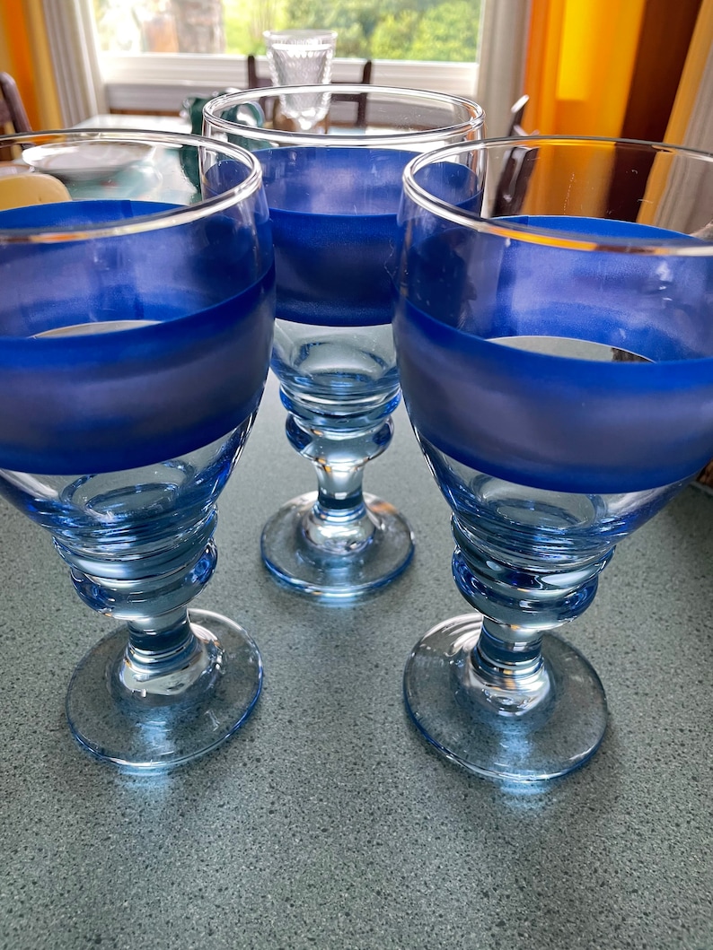 K&ouml;nnte beinhalten: Drei blaue und klare Glaskelche mit einem blauen Streifen um die Mitte jedes Kelches.