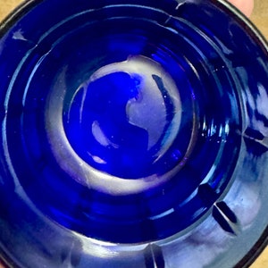 May include: A close-up view of the inside of a cobalt blue glass bowl. The bowl has a smooth, rounded bottom and a slightly flared rim.