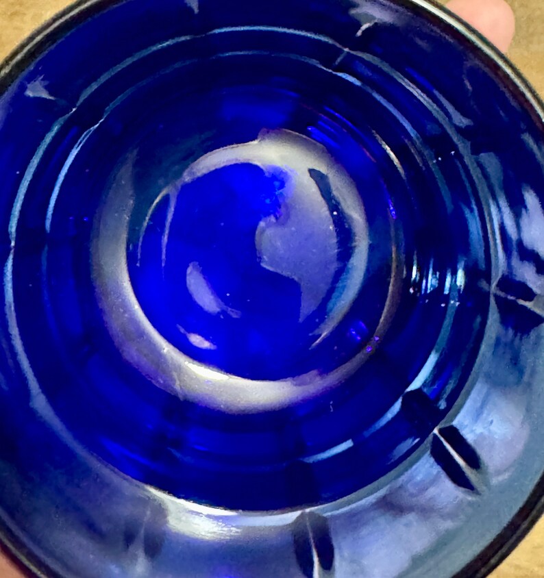 May include: A close-up view of the inside of a cobalt blue glass bowl. The bowl has a smooth, rounded bottom and a slightly flared rim.