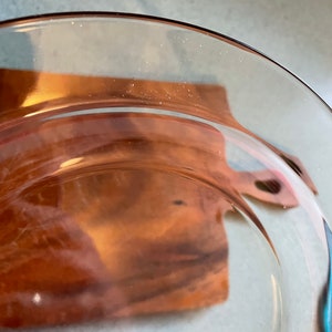 May include: A clear glass plate with a brown rim. The plate is slightly curved and has a smooth surface.