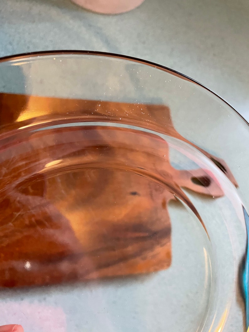 May include: A clear glass plate with a brown rim. The plate is slightly curved and has a smooth surface.