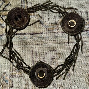 May include: A brown twig wreath with three candle holders. Each holder is a woven basket with a circular opening for a candle.