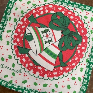May include: A square, white Christmas pot holder with a red and green bell design. The bells have red and green stripes and are tied with a green bow. The border is green with a holly leaf pattern. The brand name "FRANCO" is printed on the pot holder.