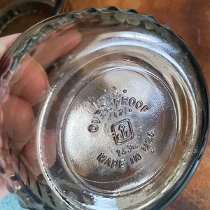 May include: Close-up of the bottom of a clear glass bowl with a textured rim. The bowl is marked "Oven-Proof 17" with a logo and "1434 Made in USA".