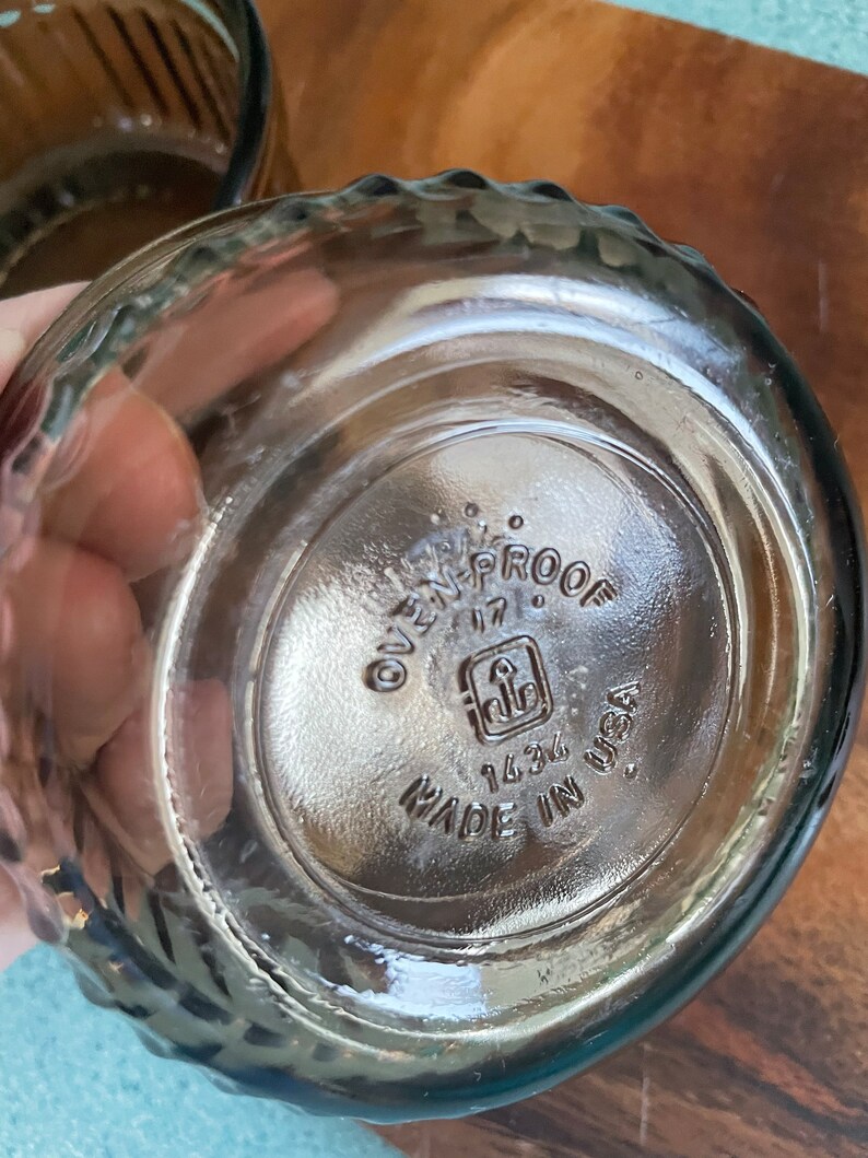 May include: Close-up of the bottom of a clear glass bowl with a textured rim. The bowl is marked "Oven-Proof 17" with a logo and "1434 Made in USA".