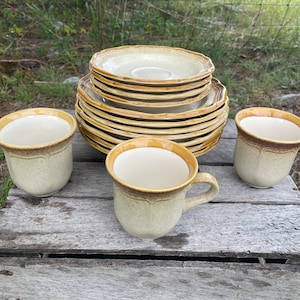 May include: Set of four beige and brown ceramic mugs with a stack of beige and brown ceramic saucers.