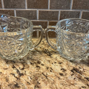 May include: A vintage glass creamer and sugar bowl set with a clear, diamond-shaped pattern. The set is made of clear glass and has a delicate, elegant design.