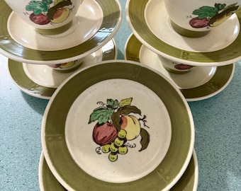 May include: Set of four vintage teacups and saucers with a green and white fruit design. The cups and saucers feature a green band with a white rim and a fruit motif in the centre.