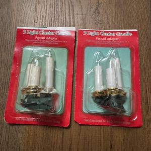 May include: Two packages of 3 light cluster candles with pigtail adapters. The packages are red and white with the text "3 Light Cluster Candle" and "Pig-tail Adapter".