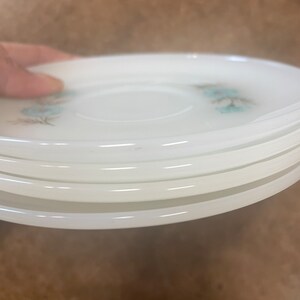 Puede incluir: Una pila de seis platillos de cer&aacute;mica blanca con un delicado dise&ntilde;o floral azul. Los platillos est&aacute;n apilados uno encima del otro, con el platillo superior ligeramente inclinado.