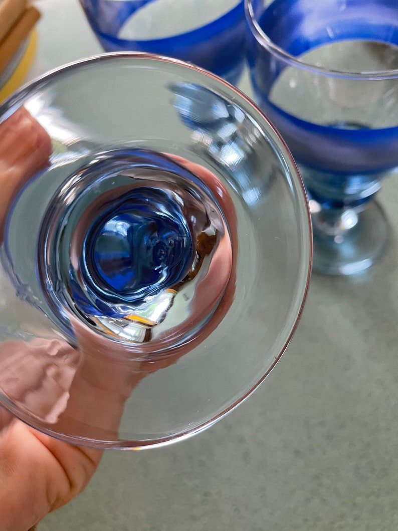 K&ouml;nnte beinhalten: Ein klares Glas mit einem blau-wei&szlig; gestreiften Design. Das Glas wird auf den Kopf gestellt, wodurch das Innere des Glases sichtbar wird.