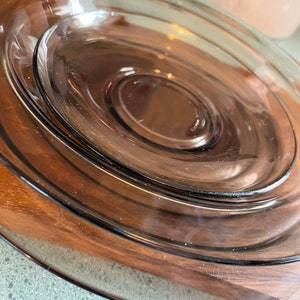 May include: A set of three brown glass plates stacked on top of each other. The plates are round and have a smooth, glossy finish.