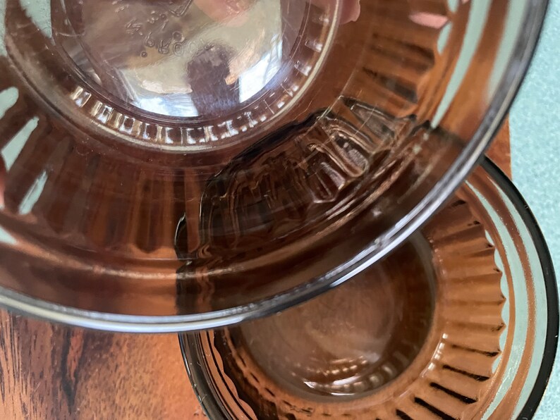 May include: Two clear glass bowls with a brown tint and a fluted edge. The bowls are nested together.