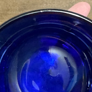 May include: A close-up view of the inside of a cobalt blue glass bowl. The bowl is round and has a smooth, reflective surface.