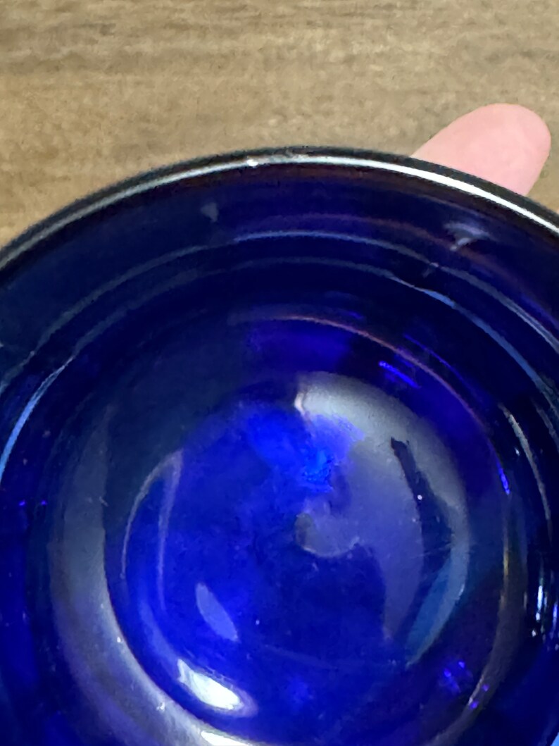 May include: A close-up view of the inside of a cobalt blue glass bowl. The bowl is round and has a smooth, reflective surface.