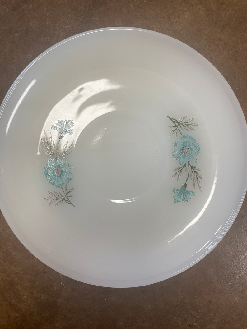 Puede incluir: Taz&oacute;n de cer&aacute;mica blanco con un dise&ntilde;o floral con flores azules y verdes. El taz&oacute;n es perfecto para servir aperitivos o postres.