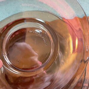 May include: A clear glass plate with a brown tint. The plate has a raised edge and a smooth surface. The bottom of the plate has the text "arc international" printed on it.