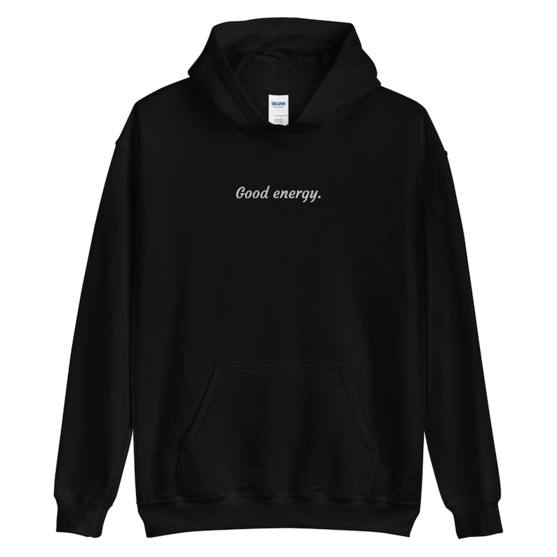 May include: Black hooded sweatshirt with a front pocket and drawstring. The phrase "Good energy." is printed in a cursive font across the chest. The sweatshirt is made of a soft material.