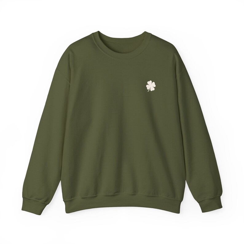 May include: Olive green sweatshirt with a small, off-white four-leaf clover embroidered on the left chest. The long-sleeved crew neck top is made of a soft material and is suitable for casual wear. The sweatshirt is a solid color.