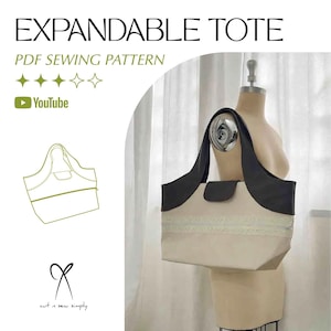 Może przedstawiać: Rozkładana torba typu tote z kremowym korpusem i ciemnoszarymi akcentami. Torba posiada zapięcie na klapę i ozdobne wykończenie. Tekst na zdjęciu brzmi "EXPANDABLE TOTE" i "PDF SEWING PATTERN". Widoczny jest również rysunek linii torby.