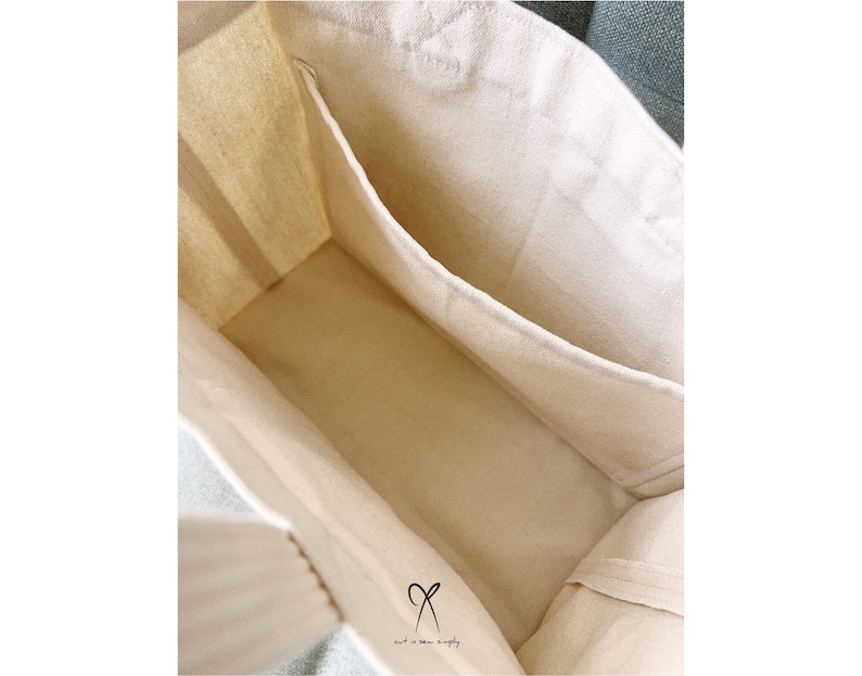 May include: A white canvas tote bag with a single interior pocket. The bag is unlined and has a natural cotton feel.