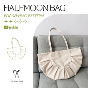 Op de afbeelding: Een beige halvemaanvormige draagtas met een geplooid ontwerp. De tas heeft lange handvatten en is gemaakt van een stevige stof. Tekst op de afbeelding luidt "HALFMOON BAG" en "PDF SEWING PATTERN". Een YouTube-logo is ook zichtbaar.