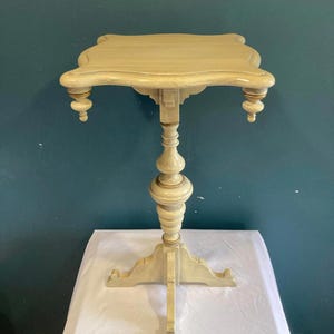 Mesa auxiliar vintage con pedestal y tablero festoneado, acabado crema envejecido