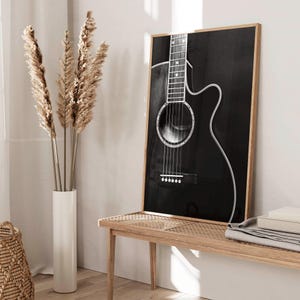 May include: Black and white photograph of an acoustic guitar with a wooden frame. The guitar is in focus and the background is blurred.