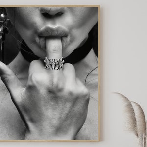 Könnte beinhalten: Schwarz-Weiß-Druck mit Rahmen, der eine Hand mit einem detaillierten Silberring am Zeigefinger zeigt. Die Lippen der Person berühren den Finger. Das Bild ist ein Porträt. Das Design des Rings ist aufwendig.
