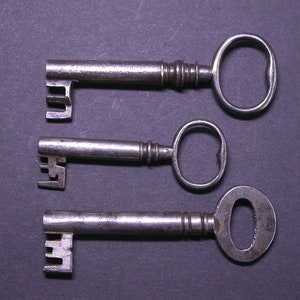 May include: Three antique keys with different shaped keyholes and intricate designs. The keys are made of metal and have a worn, aged appearance.