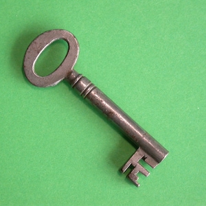 May include: A vintage metal key with an oval-shaped head and a long, narrow shaft. The key has a worn, aged appearance and is a rusty brown color.