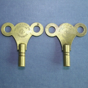 May include: Two antique brass wind-up keys with a spade symbol and the text "MADE IN ENGLAND POPULAR PROGRESS" on the top.