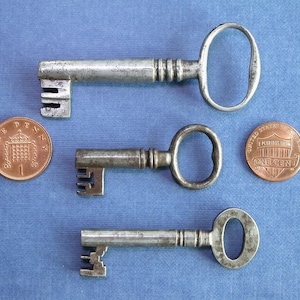 May include: Three antique keys of different sizes and styles, with a British penny and an American one-cent coin for scale.