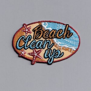 May include: A brown and beige embroidered patch with the text "Beach Clean Up" in blue and yellow lettering. The patch features a stylized image of a beach scene with waves and a starfish.