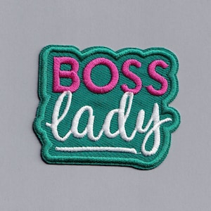 Pode incluir: Patch de feltro verde com bordado branco e rosa que diz "BOSS lady".