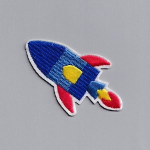 May include: A blue and red embroidered rocket patch with a yellow flame.