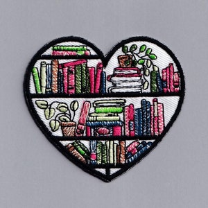 May include: A heart-shaped embroidered patch with a bookshelf design. The bookshelf is filled with colorful books and plants.