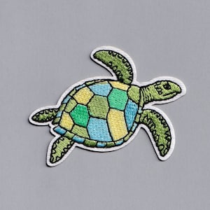 Può includere: Una toppa ricamata di una tartaruga marina verde, blu e gialla. La tartaruga sta nuotando verso destra.
